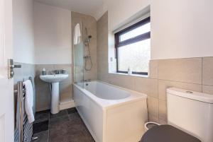 a bathroom with a tub and a sink and a toilet at Contractor-Friendly 3 Bed Home in Billingham in Norton