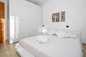 a white bedroom with a white bed and a picture at Villa Marconi Apartment 6 in Golfo Aranci