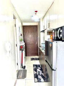 una pequeña cocina con nevera y puerta en KenZel Staycation, en Manila