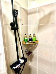 una ducha con 3 botellas en los estantes del baño en KenZel Staycation, en Manila