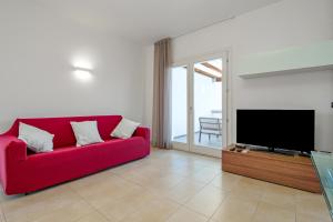 a living room with a red couch and a flat screen tv at Villa Marconi Apartment 7 in Golfo Aranci