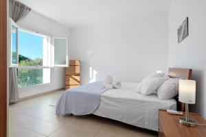 a white bedroom with a bed and a window at Villa Marconi Apartment 7 in Golfo Aranci