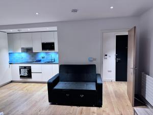 sala de estar con sofá negro y cocina en Canning Town London Hub Aptmt, en Londres