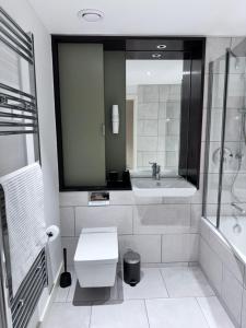 y baño con lavabo, aseo y espejo. en Canning Town London Hub Aptmt, en Londres