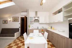 a kitchen and dining room with a white table and chairs at Casa Marisa sul Garda in Toscolano Maderno