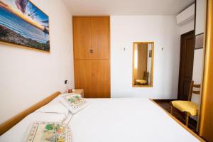 Schlafzimmer mit einem weißen Bett und einem Spiegel in der Unterkunft Casa Marisa sul Garda in Toscolano-Maderno