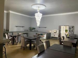 a dining room with tables and chairs and a chandelier at Beaulerland Manor House in Ermelo