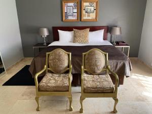 a bedroom with a large bed with two chairs at Beaulerland Manor House in Ermelo