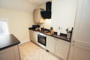 a kitchen with white cabinets and a black counter top at The Stay Company, Friar Gate Bridge. in Derby