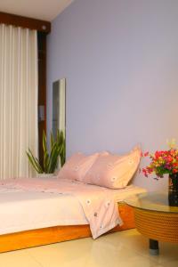 Schlafzimmer mit einem Bett mit rosa Bettwäsche und einem Tisch in der Unterkunft Keydeo Homestay - Phan thiet in Phan Thiet