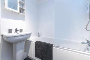 a white bathroom with a sink and a bath tub at 3 Bed Gem in Pontefract for Easy Commutes to Leeds and Wakefield in Pontefract