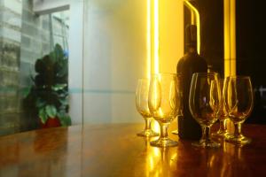vier Weingläser auf einem Tisch mit einer Flasche Wein in der Unterkunft Keydeo Homestay - Phan thiet in Phan Thiet