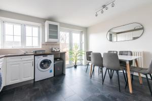 a kitchen with a washing machine and a table and chairs at 3 Bed Gem in Pontefract for Easy Commutes to Leeds and Wakefield in Pontefract