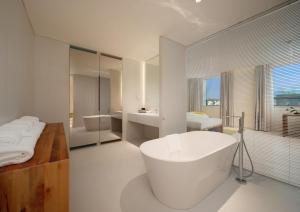 a white bathroom with a tub and a bed and a bath tub at Chengdu Chengshe Hotel - Wenjiang University Town Southwest Caida Branch in Chengdu