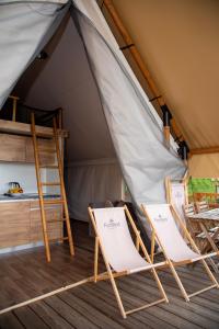 two chairs and a bed in a tent at ForRest Glamping in Banská Štiavnica