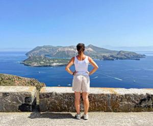 a woman standing on a wall looking at the ocean at Punta Sallustro Lipari in Lipari