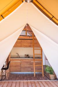 uma cama alta numa tenda com um lavatório e uma escada em ForRest Glamping em Banská Štiavnica