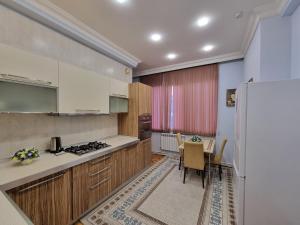 uma cozinha com armários brancos, uma mesa e um frigorífico em Bulvar apart em Baku