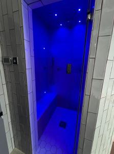 La salle de bains est pourvue d'une douche bleue et d'une baignoire. dans l'établissement Aplanty House: A Hidden Gem in The Heart of The Fens, à Wisbech