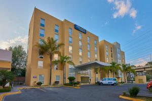 un gran edificio con un coche aparcado en un aparcamiento en City Express by Marriott Puebla FINSA, en Puebla