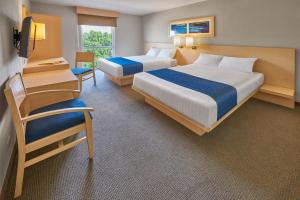 una habitación de hotel con dos camas y una silla en City Express by Marriott Puebla FINSA, en Puebla 37 fotos más