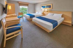 a hotel room with two beds and a chair at City Express by Marriott Puebla FINSA in Puebla