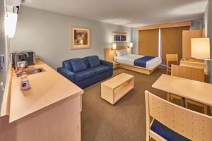 Una sala de estar con un sofá azul y una cama. en City Express by Marriott Puebla FINSA, en Puebla