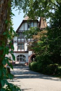 una grande casa bianca con finestre nere e alberi di Boutique Hotel Waldhaus beider Basel a Basilea