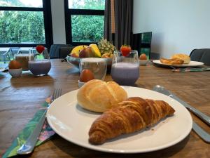 a table with a plate of bread and croissants on it at Luxe 4- persoons Veluwelodge met hottub in Ermelo! in Ermelo