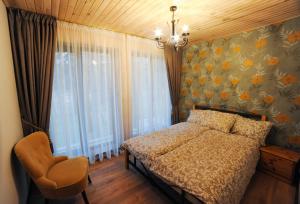 a bedroom with a bed and a chair and a window at Karčema Ružava in Molainiai