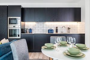 a kitchen with a table with plates and wine glasses at Modern Flat with City View in Acton in London