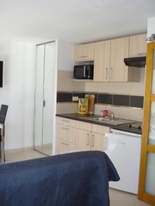 małą kuchnię z białymi szafkami i kuchenką mikrofalową w obiekcie Naturiste Cap d'Agde Villa Port Vénus 49 w Cap d'Agde