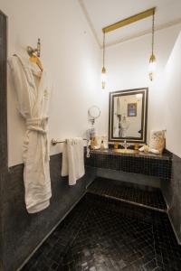 Riad la clé d'or & spa في مراكش: حمام مع حوض ومرآة ومناشف