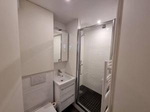 a white bathroom with a shower and a sink at Cosy Plage-Accès privé à la Mer in Cabourg +5 photos