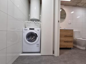 uma máquina de lavar e secar roupa numa casa de banho branca em Loft Filipinas Vibes Coruña em La Coruña
