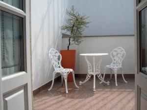 Duas cadeiras brancas e uma mesa numa varanda em Guesthouse Muralhas do Mino em Monção