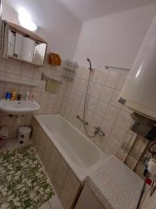 La salle de bains est pourvue d'une douche, d'une baignoire et d'un lavabo. dans l'établissement Tavas Barlang Apartman Tapolca, à Tapolca