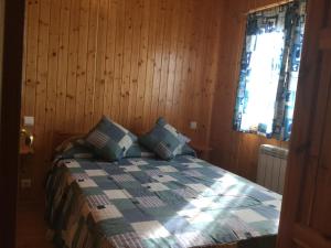 um quarto com uma cama com paredes de madeira e uma janela em Casitas Cinco Castaños em Candelario