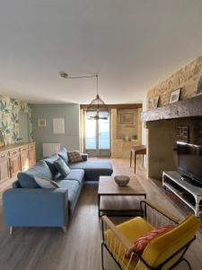 a living room with a blue couch and a television at Maison Denise - Au coeur du Périgord Noir in Castelnaud La Chapelle