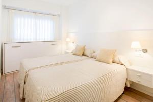 a white bedroom with a bed and a window at Beachfront and Charming Apartment in Mareny Blau