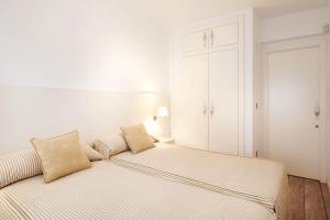 a white bedroom with a bed with pillows on it at Beachfront and Charming Apartment in Mareny Blau