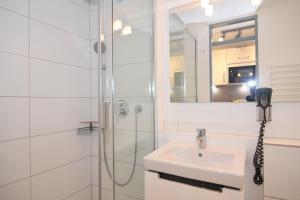 uma casa de banho branca com um lavatório e um chuveiro em Haus am Meer, Whg 154, Landseite em Westerland