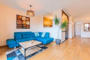 a living room with a blue couch and a table at 2 BR apartment with balconies & private parking in La Madeleine
