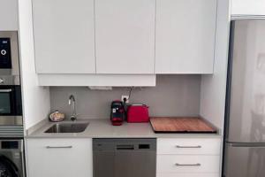 eine weiße Küche mit einer Spüle und einem Kühlschrank in der Unterkunft SHR052 Marinsa Beach Apartment in Morche