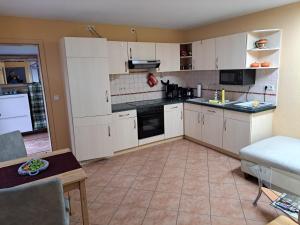 a kitchen with white cabinets and a table in a room at Ferienhaus Wilhelm Spreewald in Straupitz