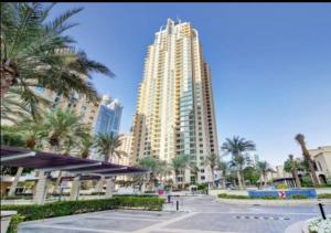 a tall building with palm trees in front of it at Urban 3BR at Al Mesk Tower Dubai Marina in Dubai