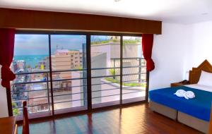 a bedroom with a bed and a large window at Highfive Hotel Pattaya in Pattaya Central