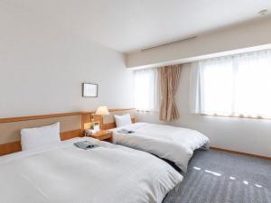 a hotel room with two beds and a window at Kochi Kuroshio Hotel in Konan