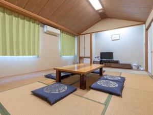 a living room with a wooden table and blue cushions at Kochi Kuroshio Hotel in Konan