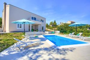 a swimming pool with chairs and umbrellas next to a house at Villa Olivia in Vrh
